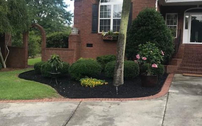 Black Rubber Mulch Landscaping Around Brick House